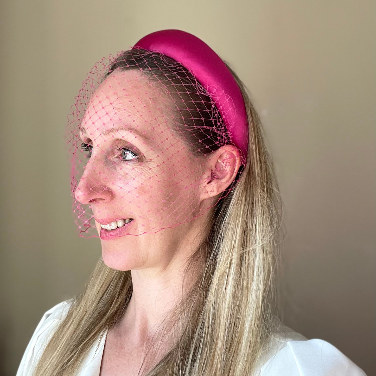 wearing pink satin padded headband with a pink net veil.