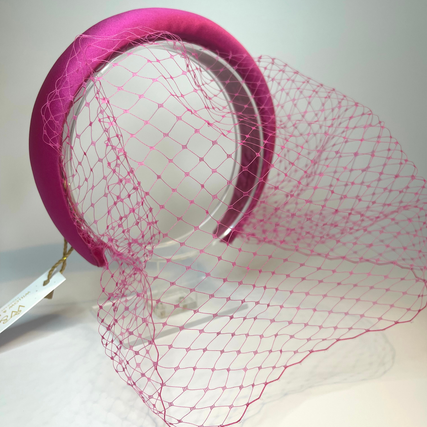 Pink satin padded headband with a pink net veil.