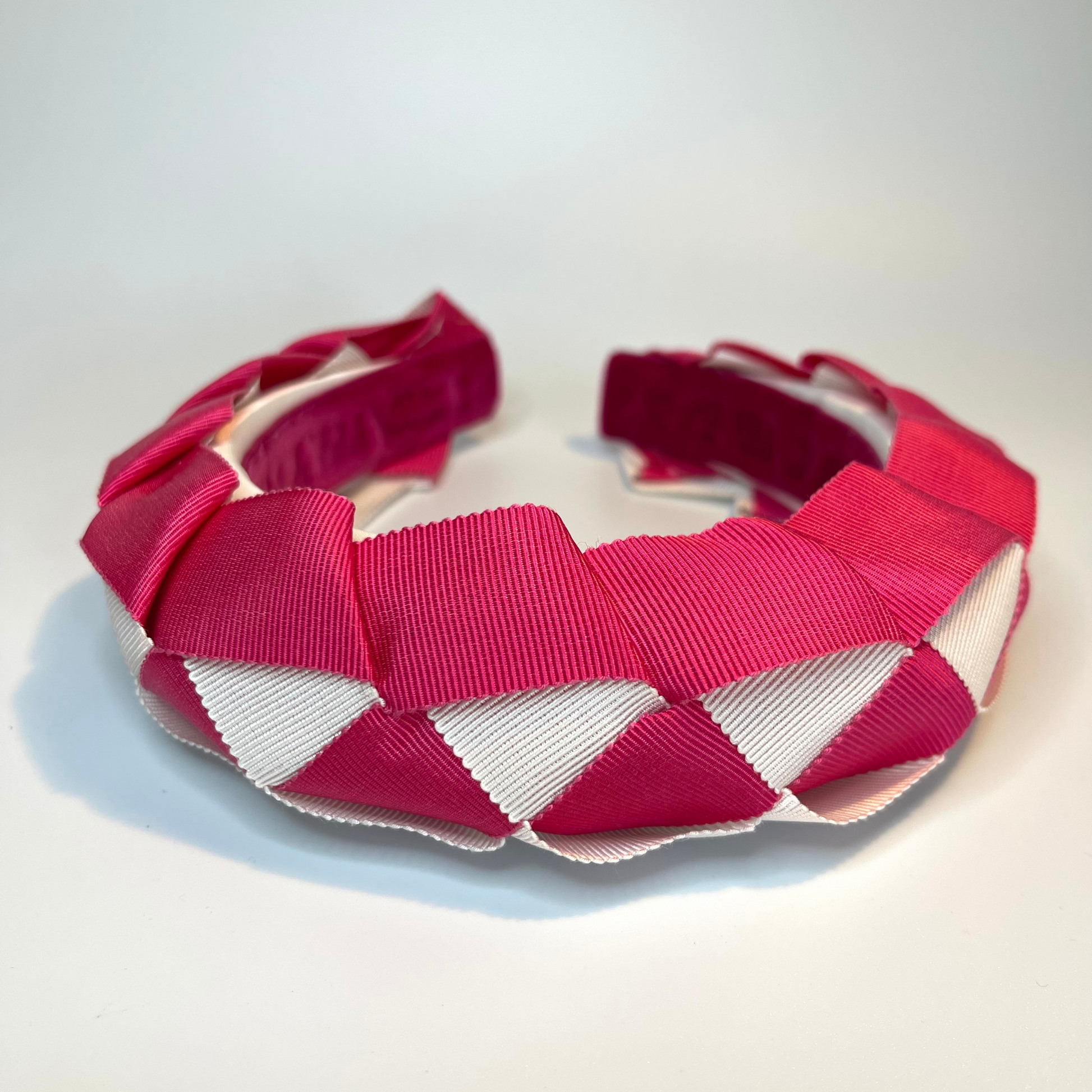 Pink and white woven ribbon sitting on a padded headband