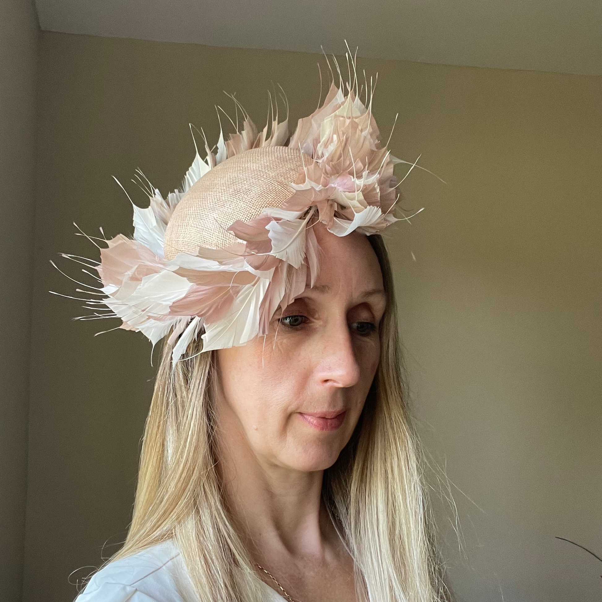 Blush and white circular feather hat on a blush sinemay base.